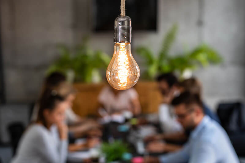 focus on light bulb with business meeting in background