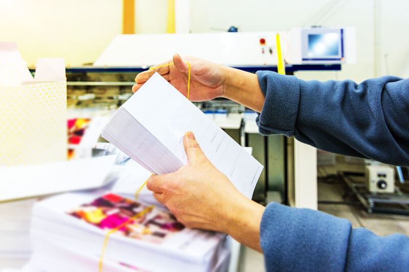 hands wrapping up a stack of printed papers