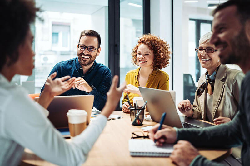 marketing professionals smiling around desktop with computers