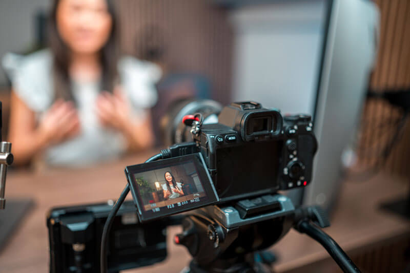 closeup on video camera pointed at woman in background