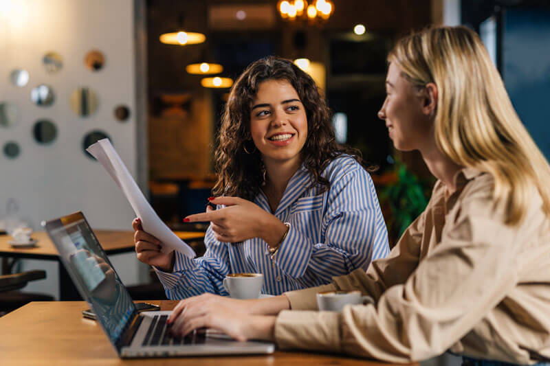 women discussing work over a laptop computer